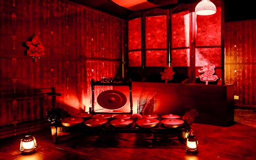 Dimly lit room with traditional Malaysian gongs and shadow puppets at Hauntu, Malaysia.