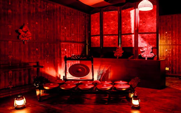 Dimly lit room with traditional Malaysian gongs and shadow puppets at Hauntu, Malaysia.