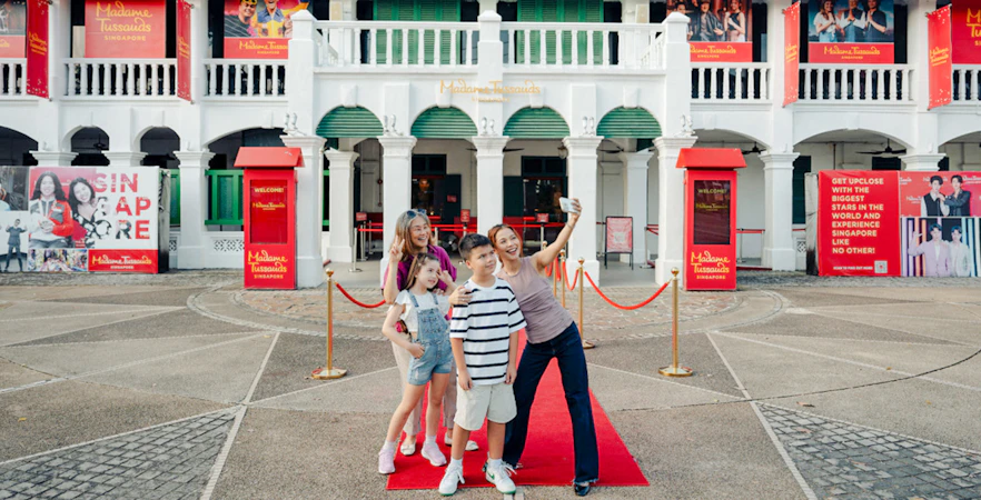 Family taking a selfie outside Madame Tussauds Singapore entrance.