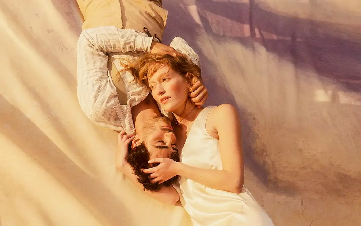 Two people lying closely together, evoking a scene from La Boheme.