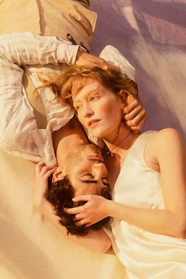 Two people lying closely together, evoking a scene from La Boheme.