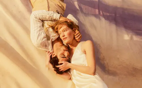 Two people lying closely together, evoking a scene from La Boheme.
