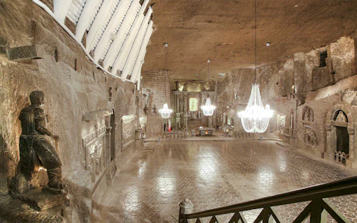 Wieliczka Salt Mine chapel with chandeliers and carved salt statues.