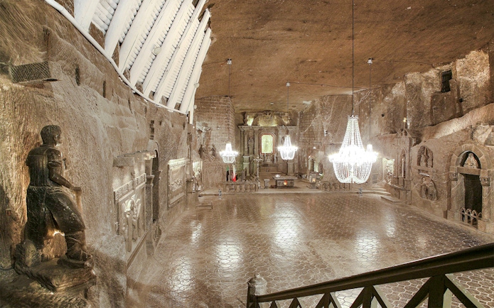 Wieliczka Salt Mine chapel with chandeliers and carved salt statues.