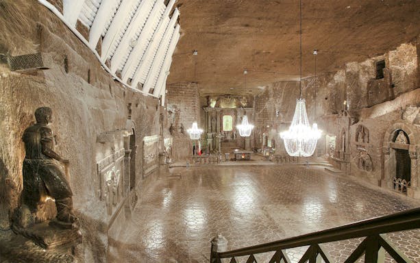Wieliczka Salt Mine chapel with chandeliers and carved salt statues.