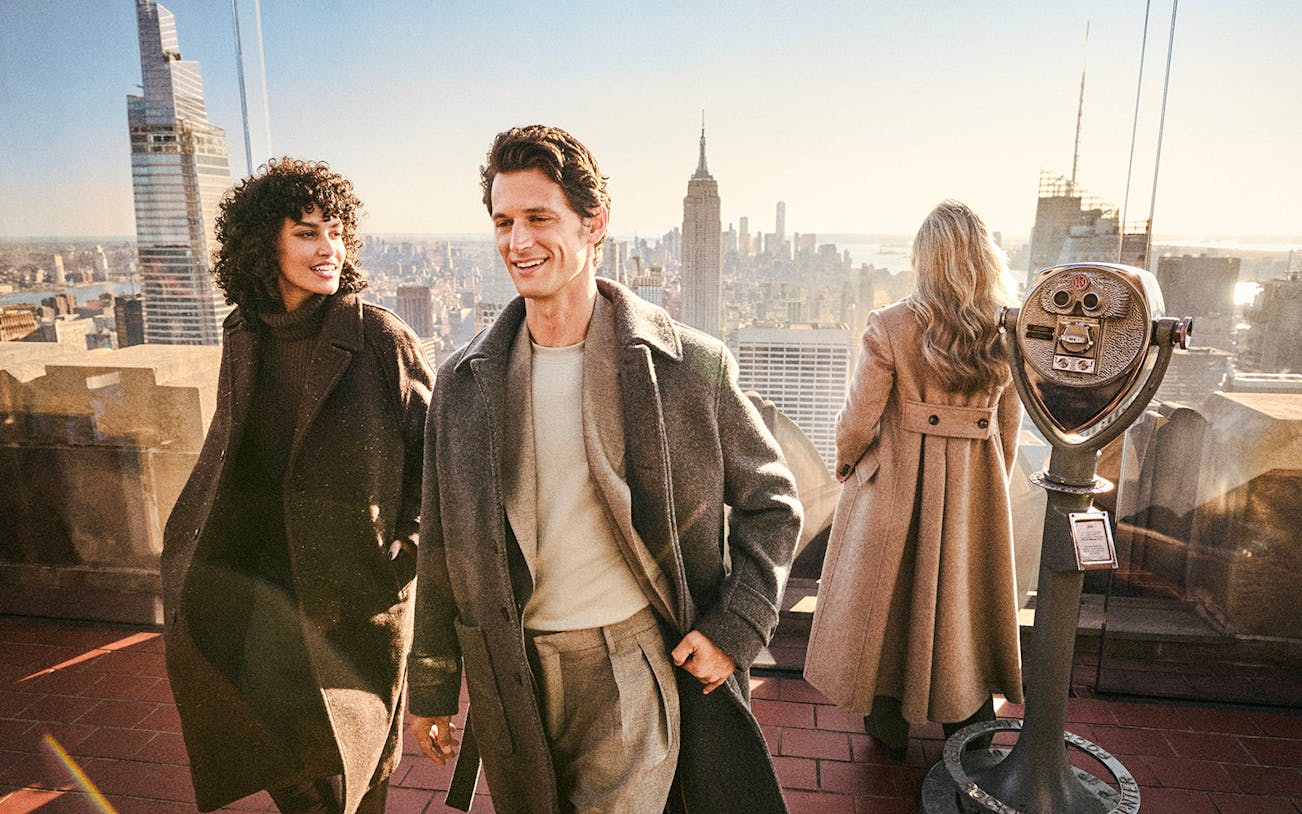 Visitors enjoying the view from Top of the Rock, New York, with the Empire State Building in the background.