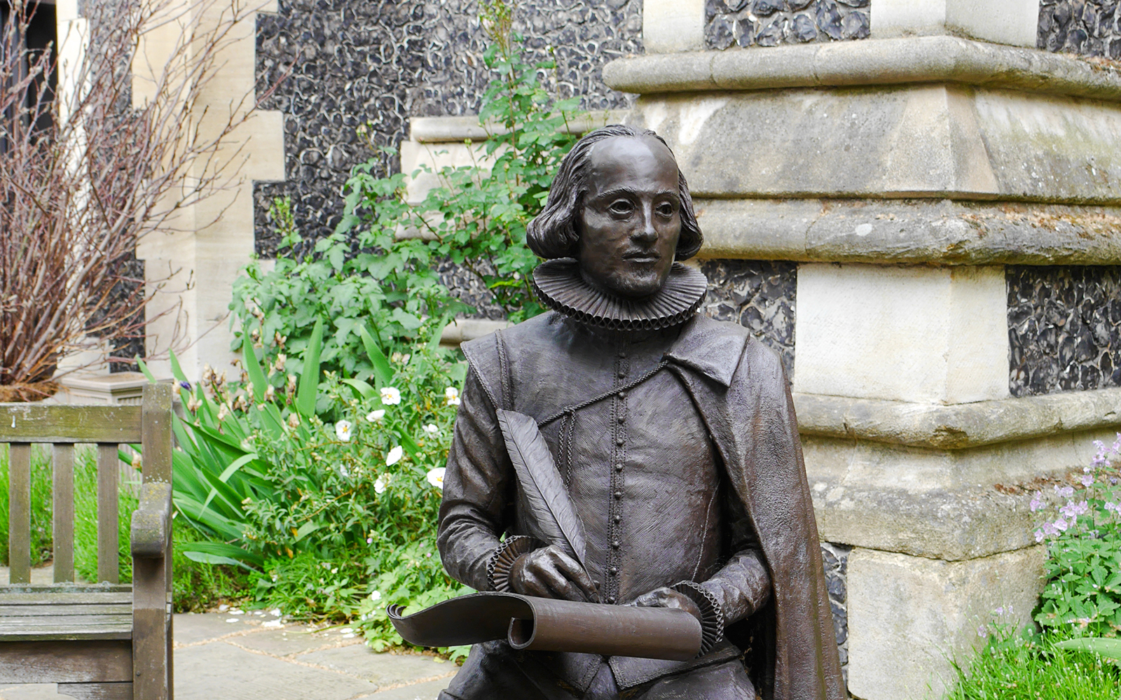 Statue of William Shakespeare holding a quill in Southwark Cathedral Churchyard.