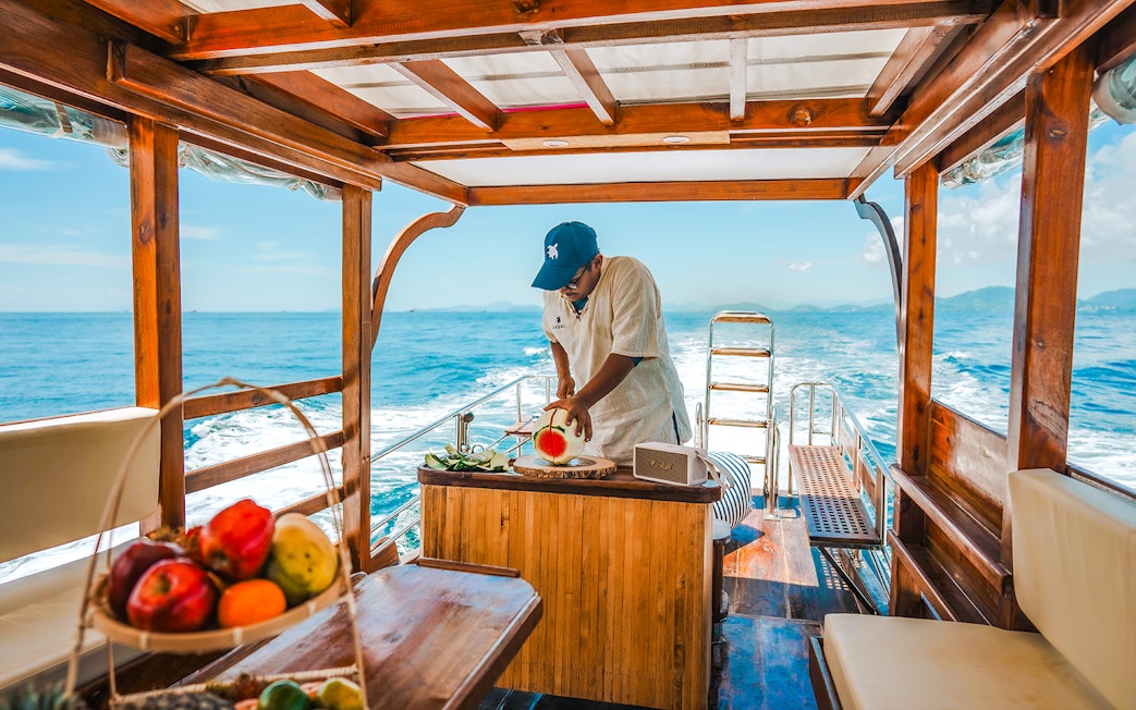 Longtail boat cruise in Krabi with a person preparing fresh fruit refreshments.