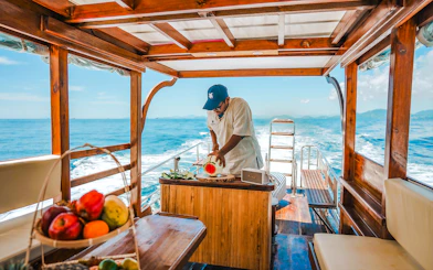 Longtail boat cruise in Krabi with a person preparing fresh fruit refreshments.