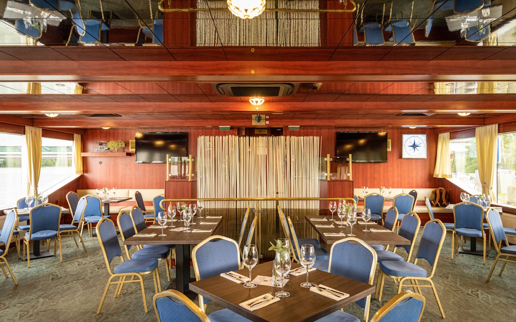 Interior of a cruise dining area with set tables and blue chairs on the Dürnstein and Wachau tour.