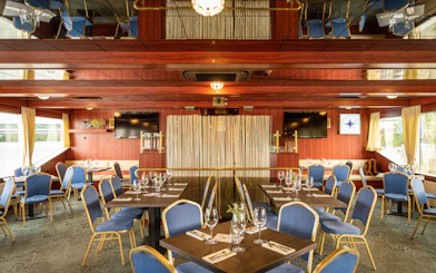 Interior of a cruise dining area with set tables and blue chairs on the Dürnstein and Wachau tour.