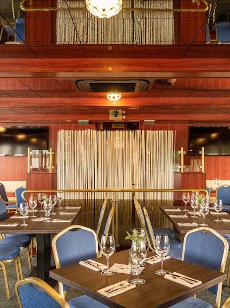 Interior of a cruise dining area with set tables and blue chairs on the Dürnstein and Wachau tour.