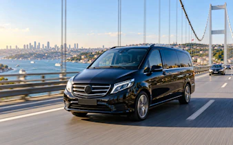 Private transfer van crossing Bosphorus Bridge, Istanbul, with city skyline in background.