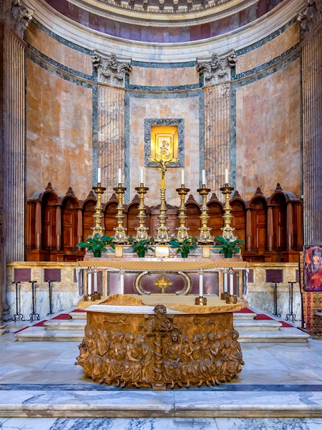 Main altar of the Pantheon in Rome with ornate carvings and golden candlesticks.