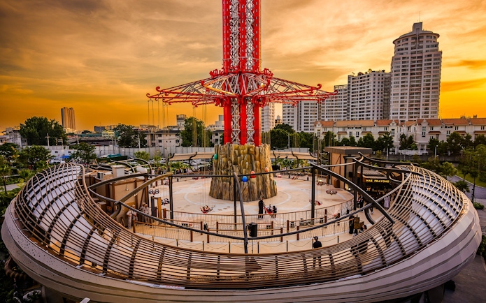 SkyFlyer ride at Asiatique Bangkok during sunset with city skyline in the background.