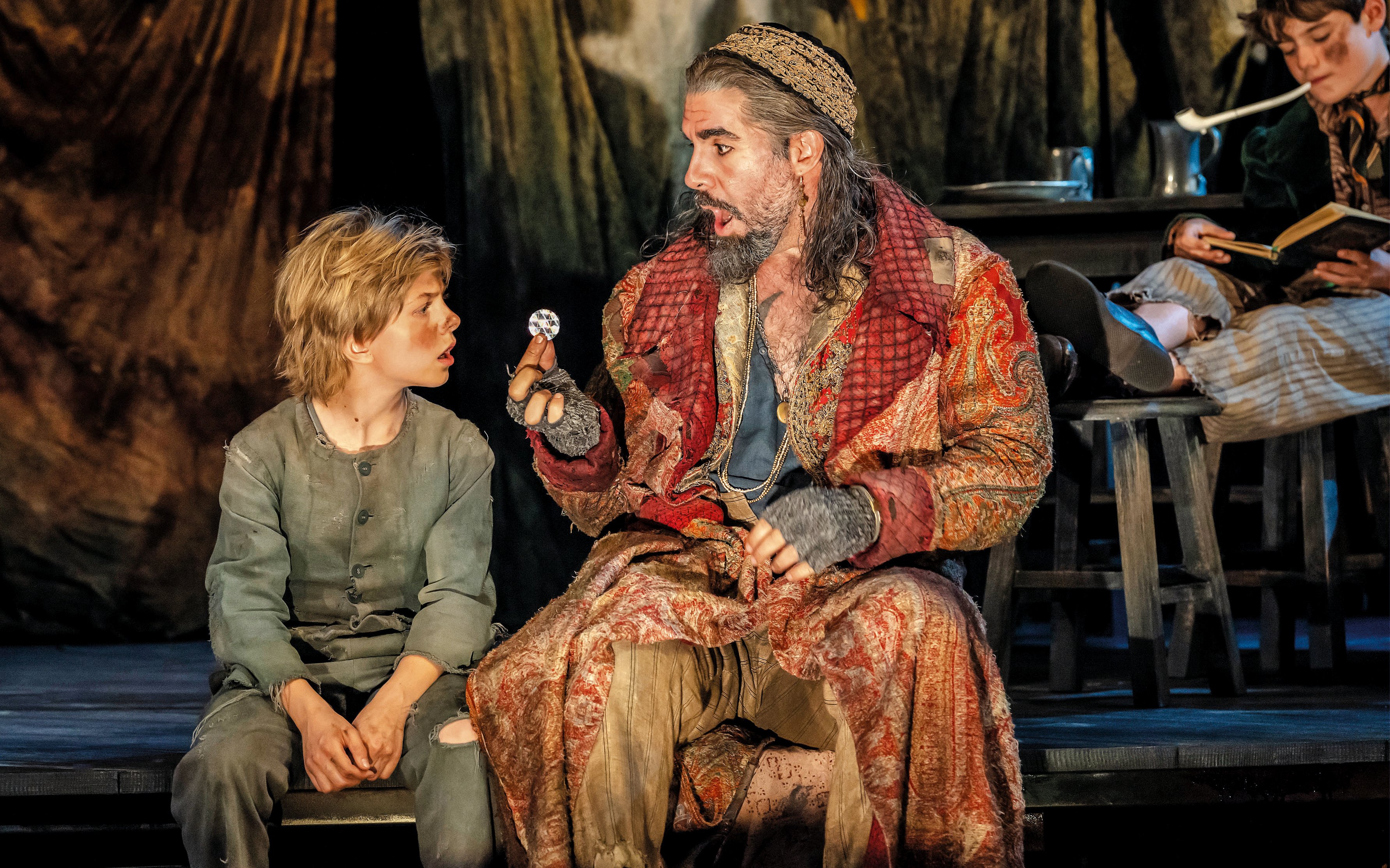 Actors in period costumes performing a scene from "Oliver" on stage.