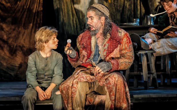 Actors in period costumes performing a scene from "Oliver" on stage.