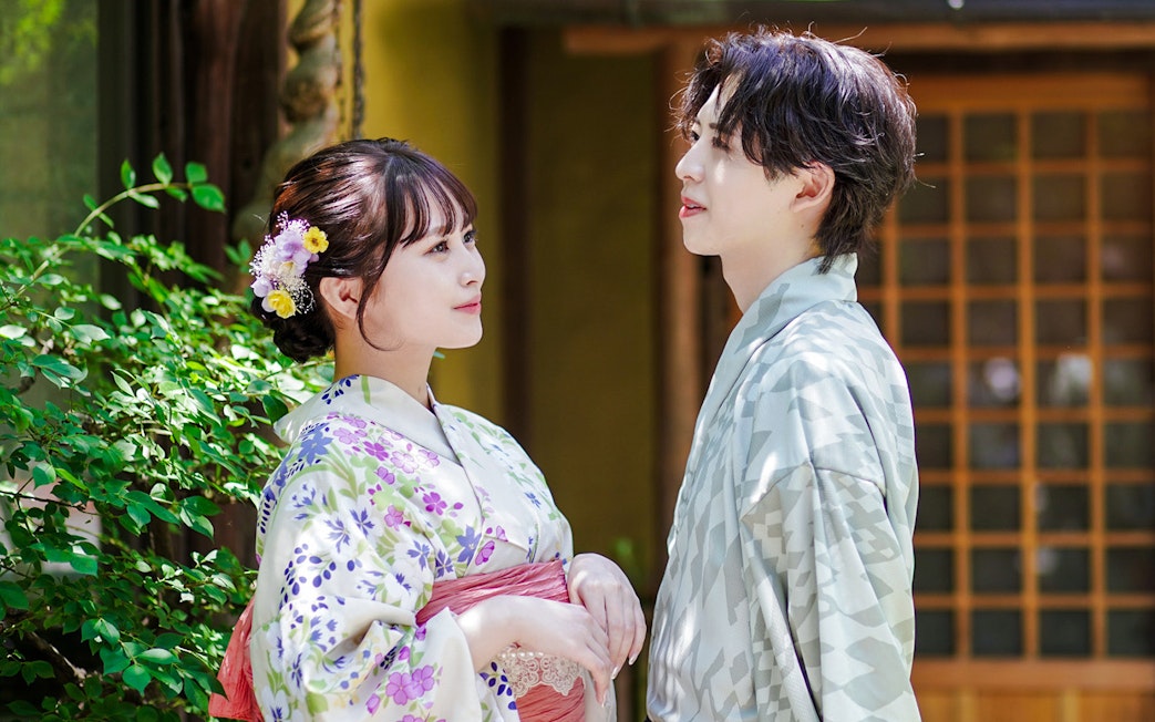 Couple in traditional kimono standing in a Japanese garden.