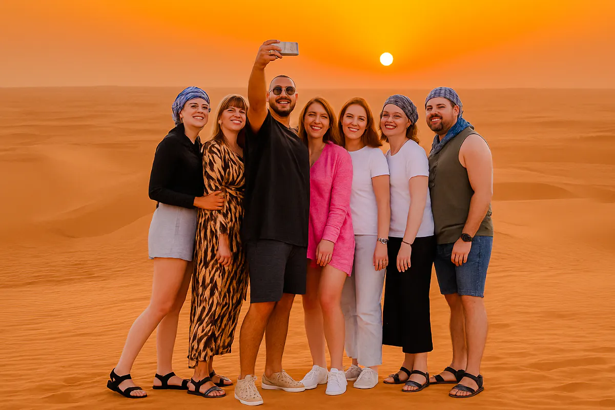 Group taking selfie during Abu Dhabi desert safari at sunset.
