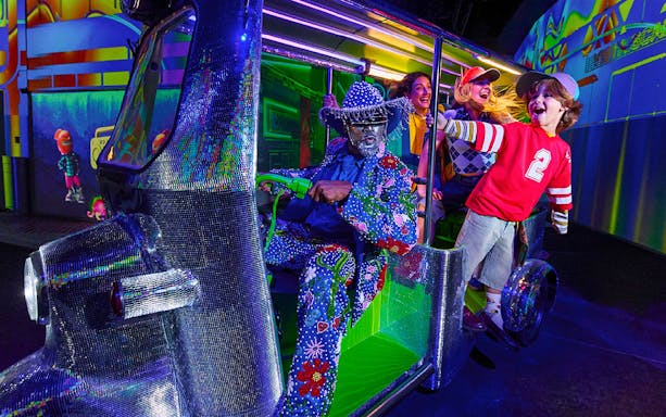 Visitors enjoying a ride with colorful characters at House Of Hype.