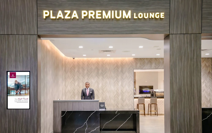 Entrance of Plaza Premium Lounge, Terminal 1, Toronto Pearson Airport, with reception desk and staff.