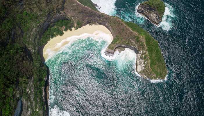Aerial view of Kelingking Beach's cliff and turquoise waters, Nusa Penida, Bali.