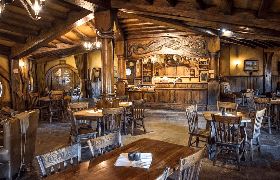 Interior of the Green Dragon Inn at Hobbiton Movie Set with wooden tables and chairs.