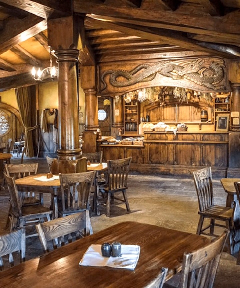 Interior of the Green Dragon Inn at Hobbiton Movie Set with wooden tables and chairs.