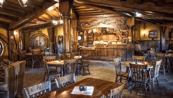 Interior of the Green Dragon Inn at Hobbiton Movie Set with wooden tables and chairs.