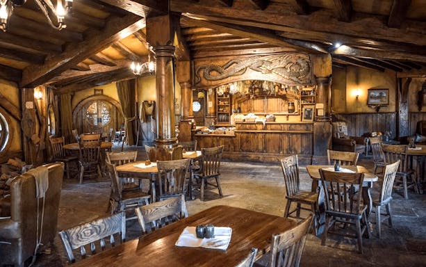 Interior of the Green Dragon Inn at Hobbiton Movie Set with wooden tables and chairs.