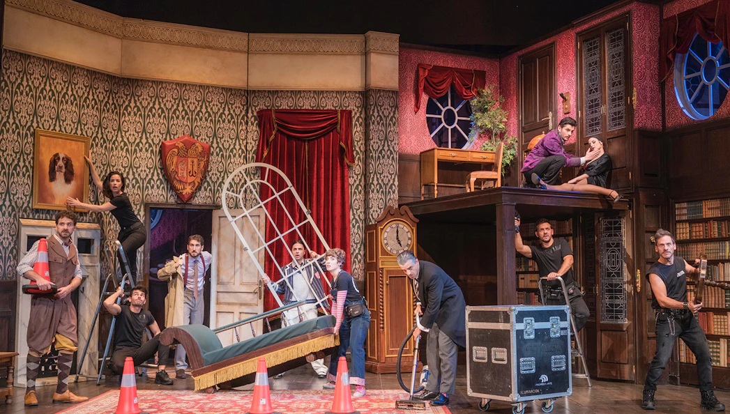 Theater cast performing a chaotic scene in "La Función Que Sale Mal" with props and set pieces.