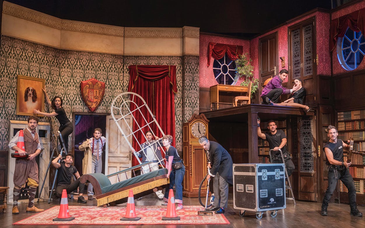 Theater cast performing a chaotic scene in "La Función Que Sale Mal" with props and set pieces.