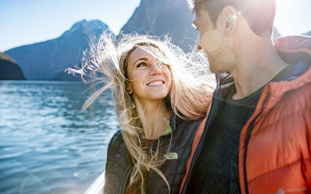 Couple enjoying a cruise on Milford Sound with mountains in the background.