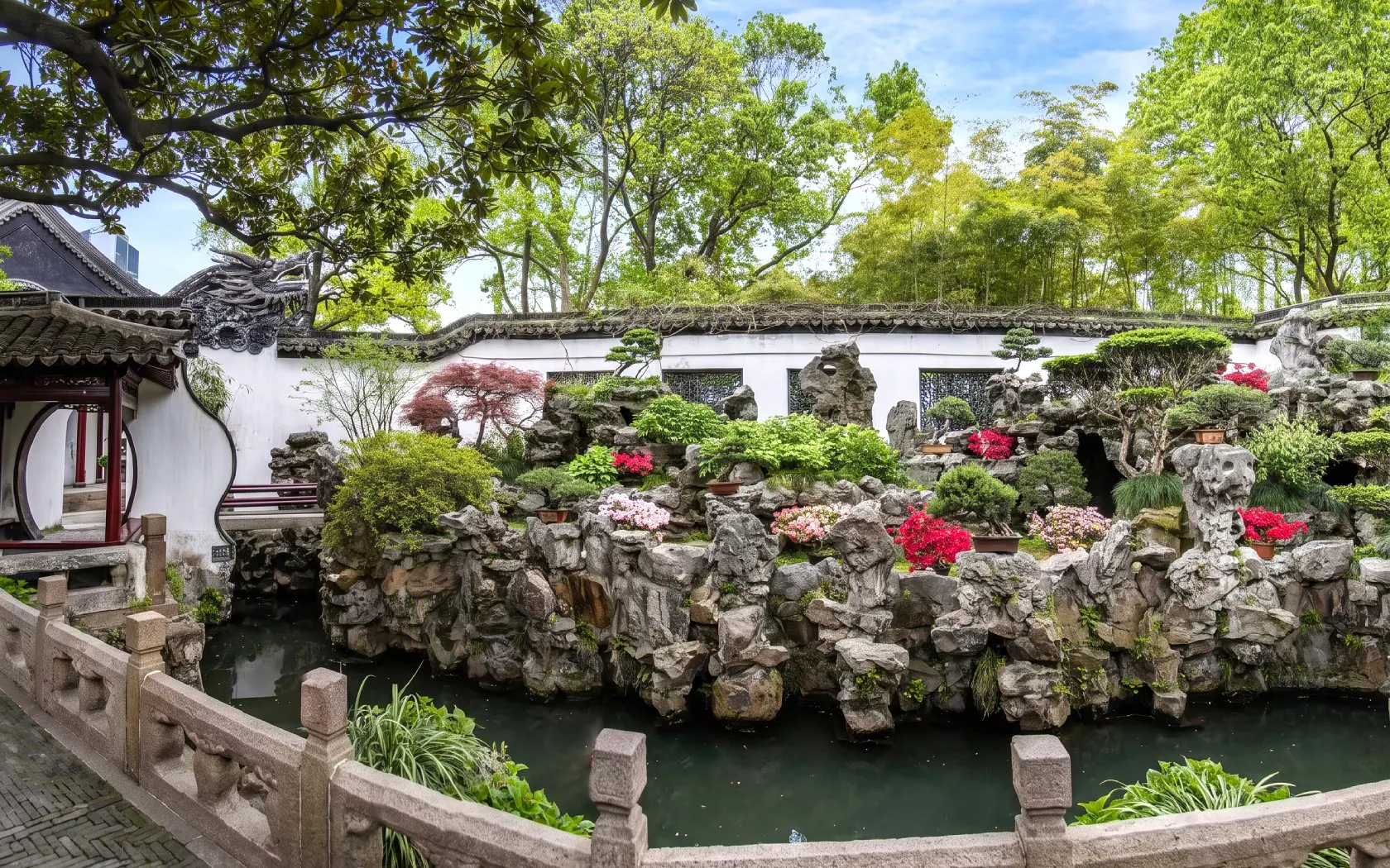 Yu Garden rockery and pond with lush greenery and traditional architecture, Shanghai, China.
