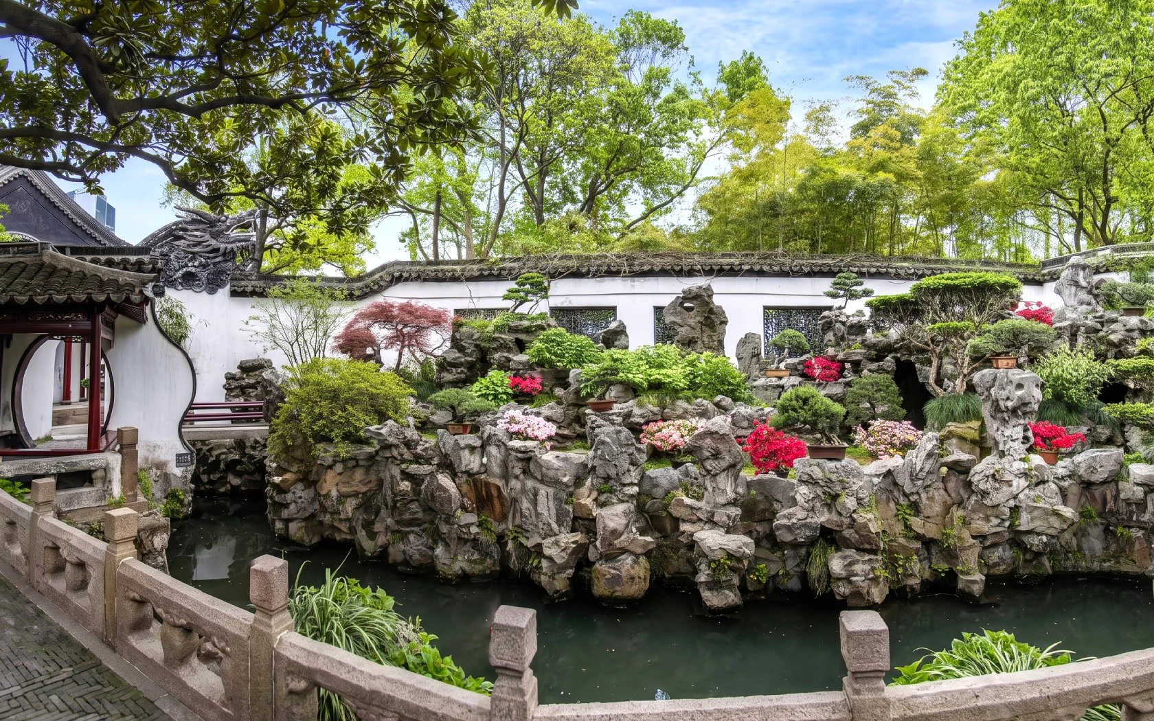 Yu Garden rockery and pond with lush greenery and traditional architecture, Shanghai, China.