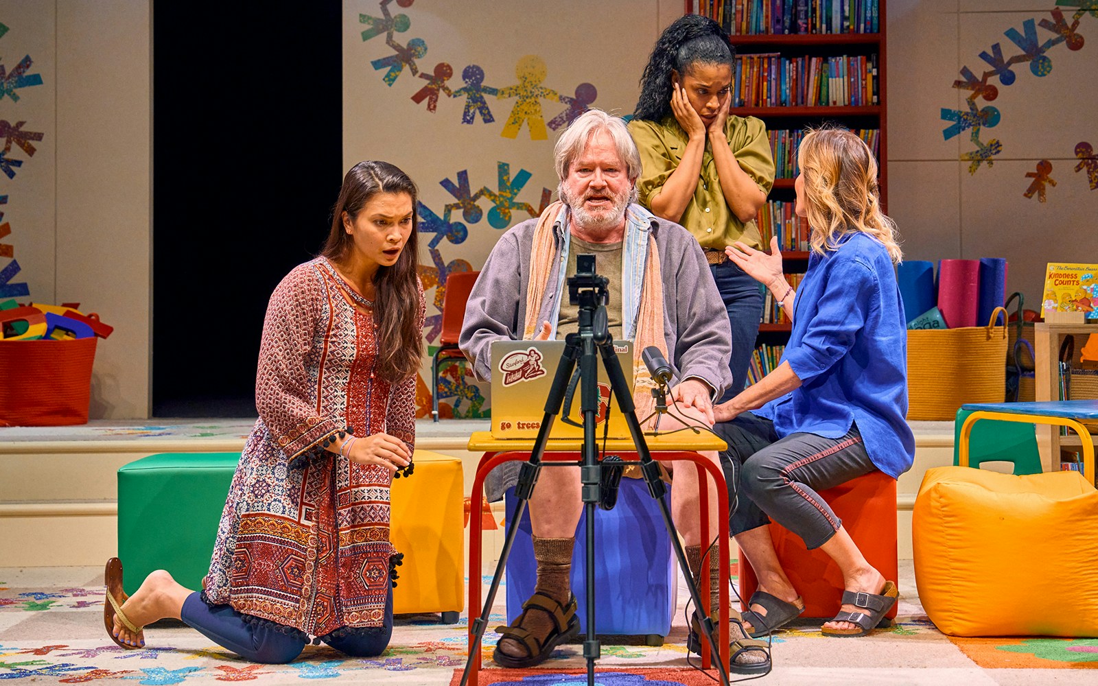 Group of actors performing a scene from "Eureka Day" in a colorful classroom setting.