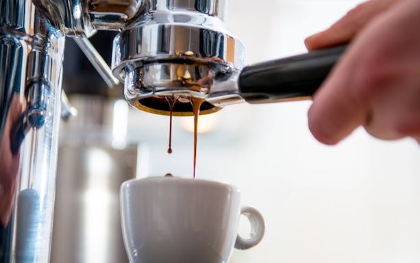 Espresso pouring into cup at Michelin star breakfast in Paris.