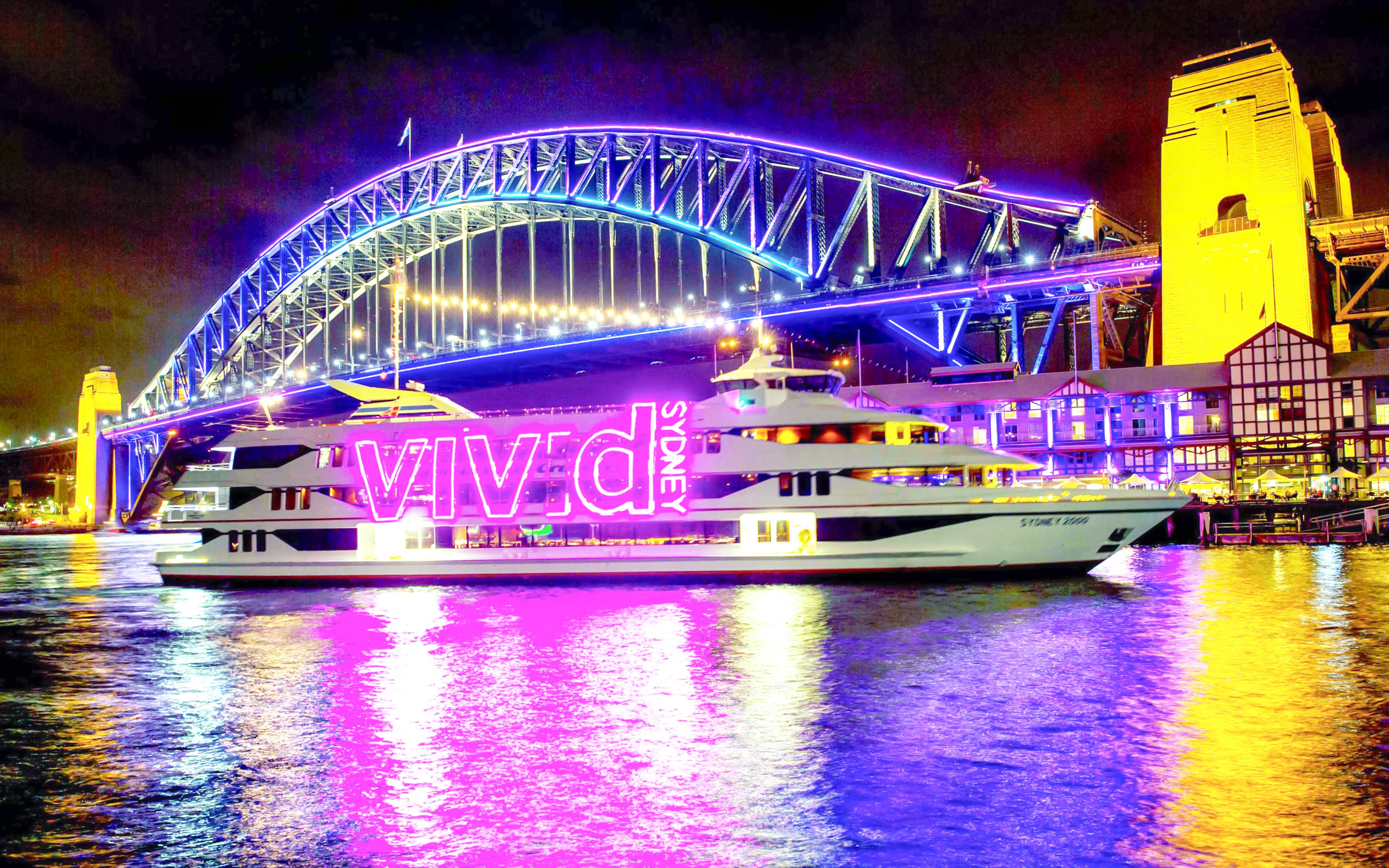 Sydney Harbour Bridge illuminated during Vivid Sydney light show with cruise ship in foreground.
