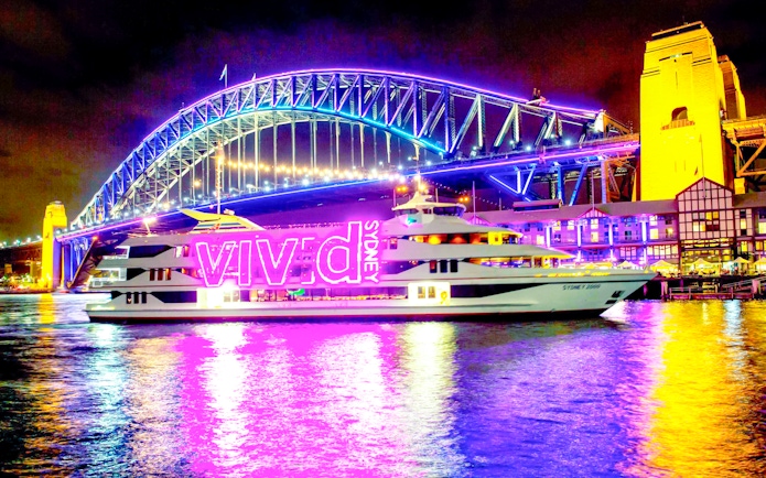 Sydney Harbour Bridge illuminated during Vivid Sydney light show with cruise ship in foreground.