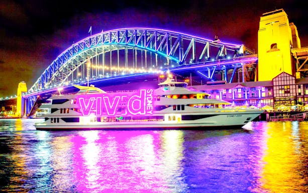 Sydney Harbour Bridge illuminated during Vivid Sydney light show with cruise ship in foreground.
