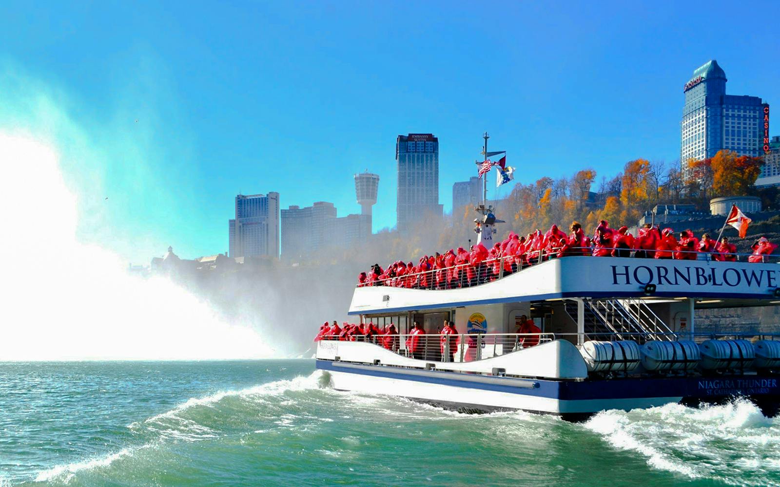 Tour boat approaching Niagara Falls, Canada with passengers in red ponchos.