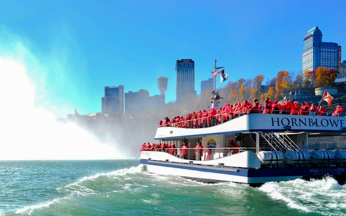 Tour boat approaching Niagara Falls, Canada with passengers in red ponchos.