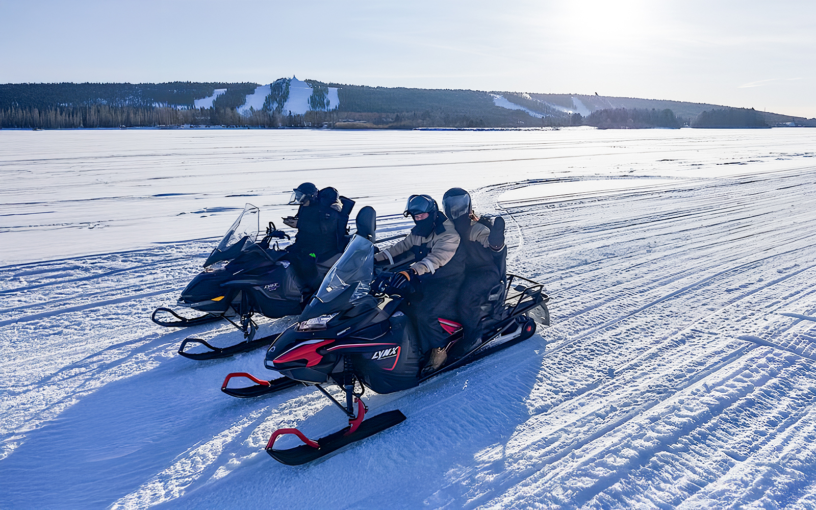Snowmobilers on frozen lake in Lapland during winter.