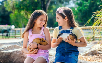 Girls holding guinea pigs at Paradise Country animal nursery, Gold Coast.