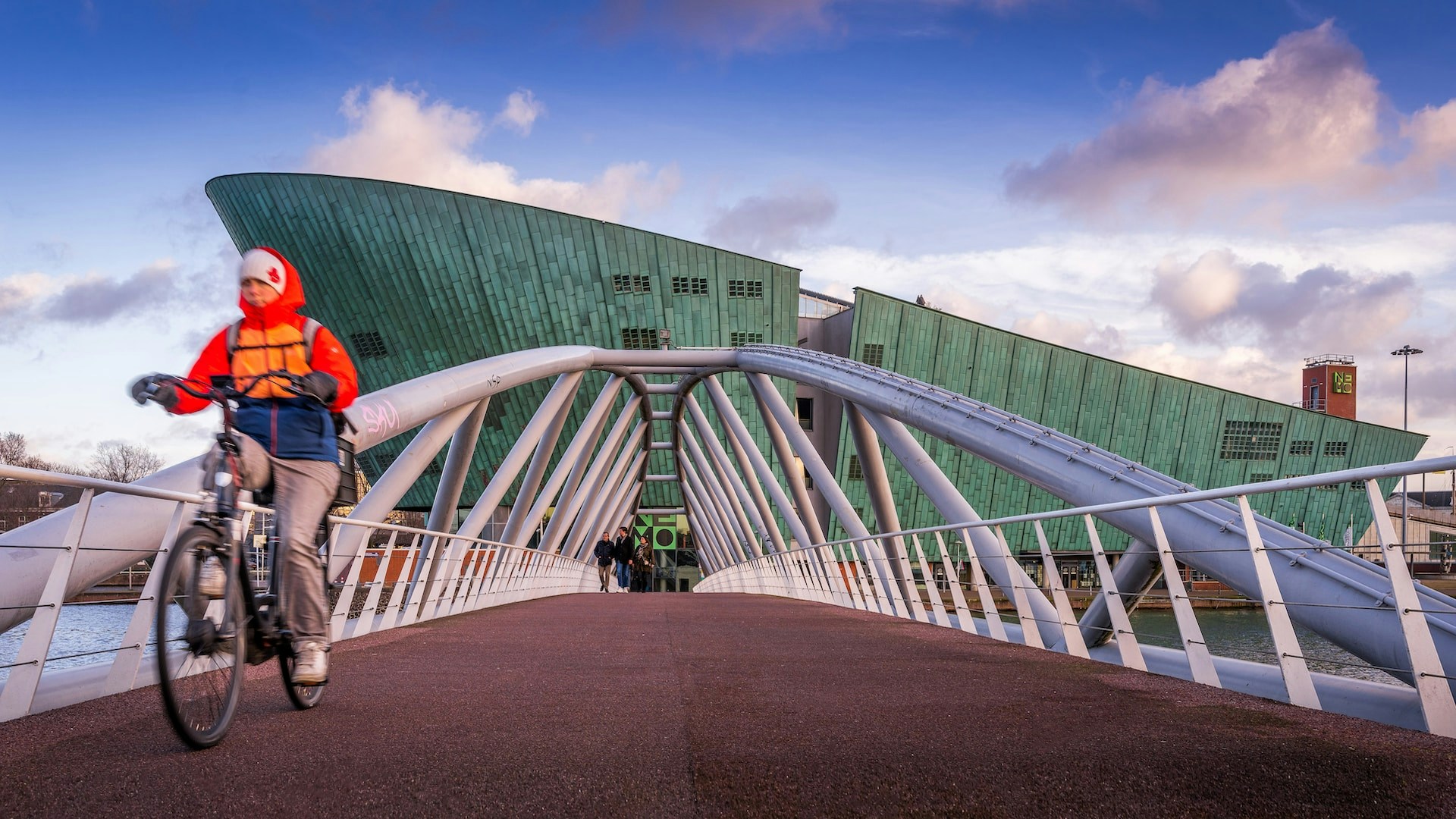 Cyclist crossing bridge towards NEMO Science Museum in Amsterdam.