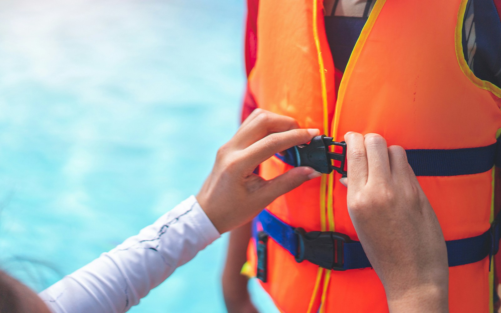 Person fastening a life jacket buckle for Black Boats Tours.