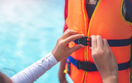 Person fastening a life jacket buckle
