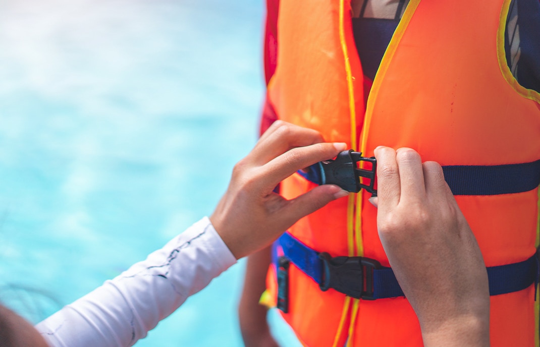 Person fastening a life jacket buckle