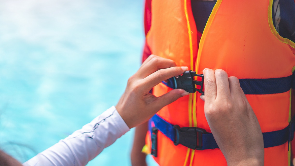 Person fastening a life jacket buckle for Black Boats Tours.