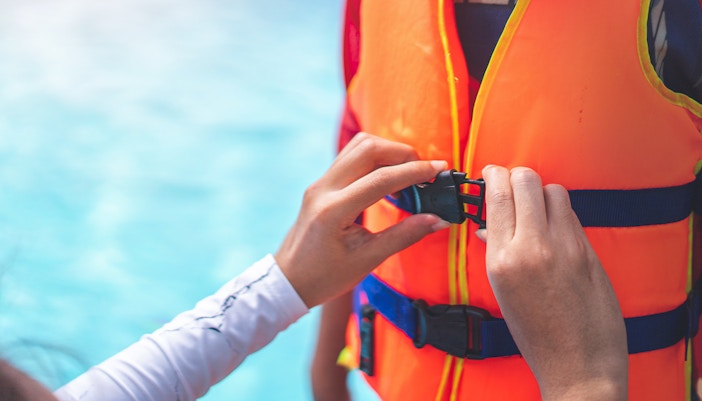 Person fastening a life jacket buckle for Black Boats Tours.